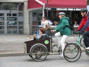 Kia Andreasson cyklar mp-cykelvagnen med en trumpetare i (som var del av ett jättesvängigt cyklande klezmerband!)